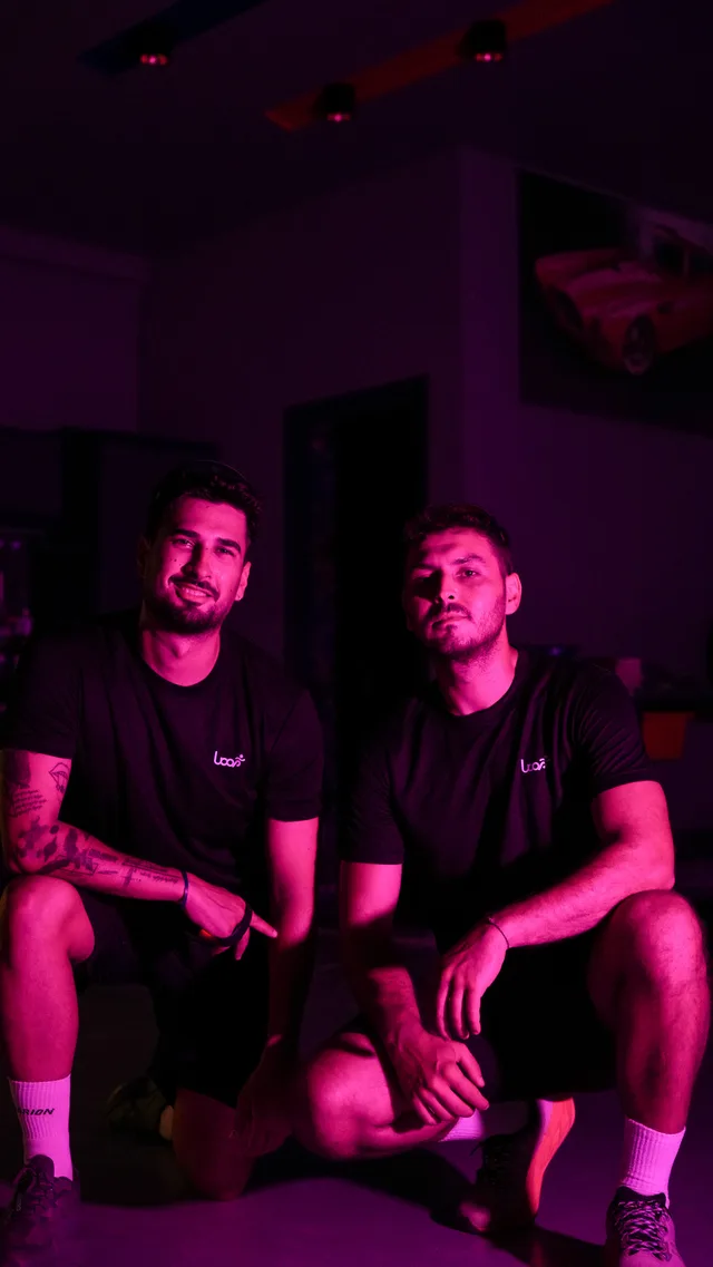 Pembe ışıklar altında Loop tişörtleriyle iki katılımcı